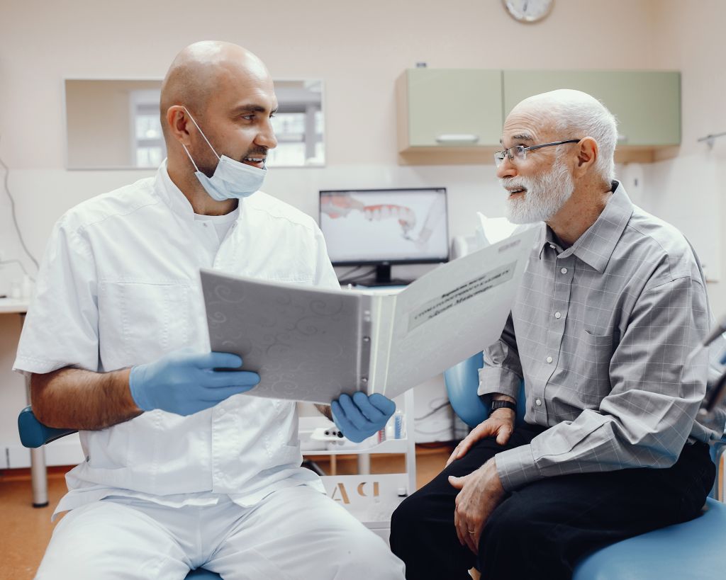 Senior man seated in dentist’s office receiving consultation under Canadian Dental Care Plan